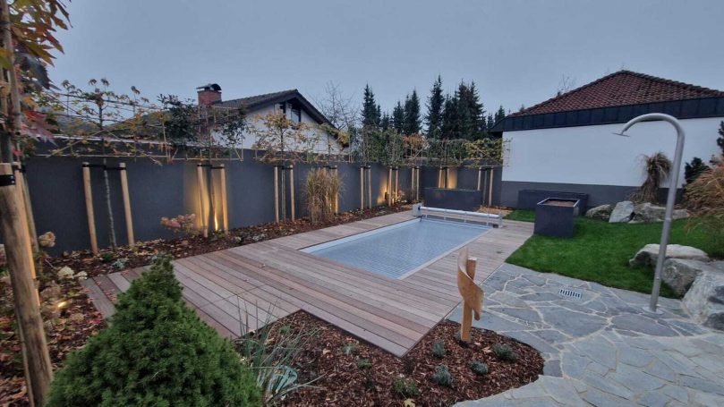 Pool mit Holzterrasse und Beleuchtung